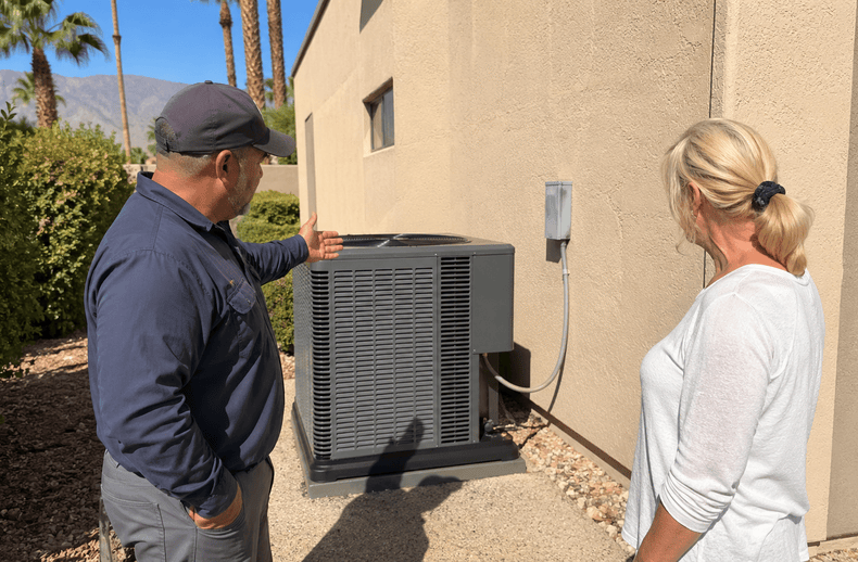 A technician explaining heat pump replacement costs in the Coachella Valley.